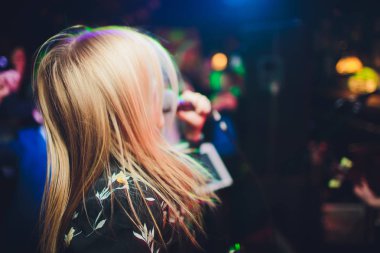 Bir mikrofon şarkı ve tatil parlayan arka plan üzerinde dans ile Güzellik modeli kız şarkıcı. Karaoke partisi şarkıcısı. Disko partisi. Kutlama.