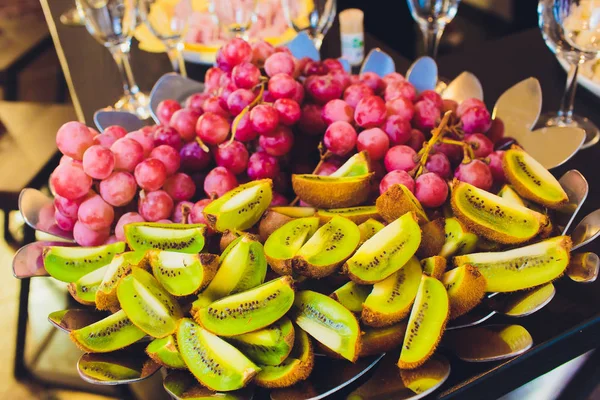 Primo piano di uve rosse biologiche fresche e mature su un lussuoso buffet condito con kiwi per una sana colazione o cena . — Foto Stock