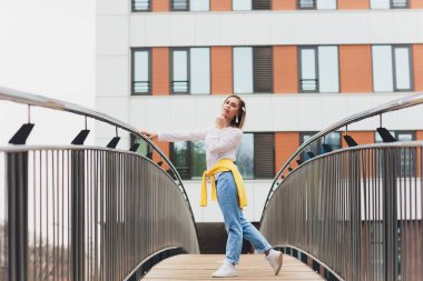 Hipster kız boş beyaz t-shirt ve kot pantolon sokak yol, minimalist kentsel giyim tarzı karşı poz giyiyor.
