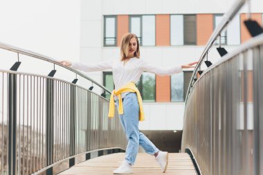 Hipster kız boş beyaz t-shirt ve kot pantolon sokak yol, minimalist kentsel giyim tarzı karşı poz giyiyor.