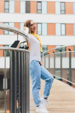Hipster kız boş beyaz t-shirt ve kot pantolon sokak yol, minimalist kentsel giyim tarzı karşı poz giyiyor.