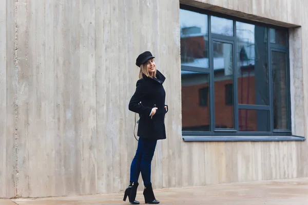 Portré divatos nő séta a városban a kabátot visel Fekete sapka. — Stock Fotó