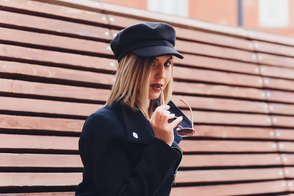 黒い帽子をかぶったコートで街を歩いているファッショナブルな女性のポートレート. — ストック写真