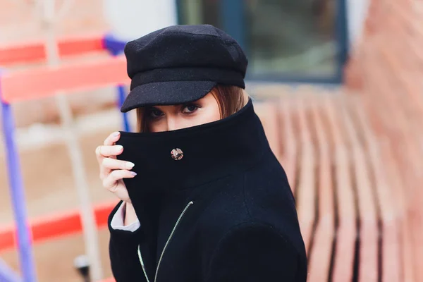 Portré divatos nő séta a városban a kabátot visel Fekete sapka. — Stock Fotó