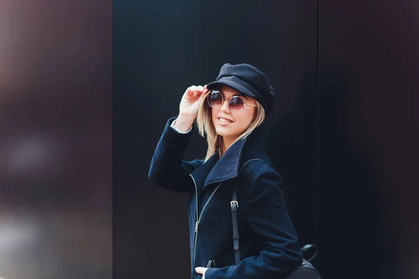 Portrait de femme à la mode marchant en ville en manteau portant un bonnet noir . — Photo