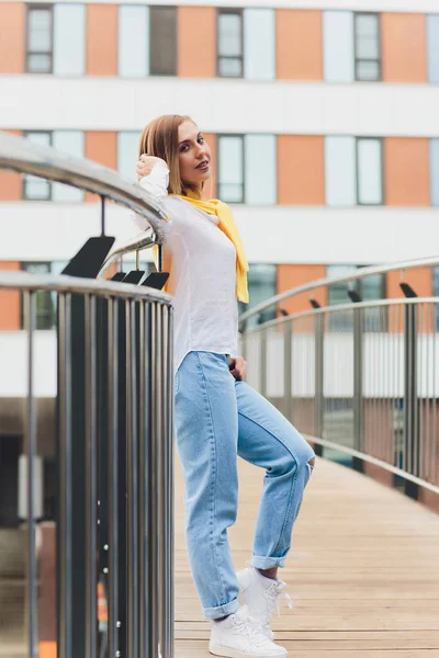 Хипстерская девушка в белой футболке и джинсах, позирующая на улице, в стиле минималистской городской одежды . — стоковое фото