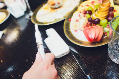 Isı yakmayan tütün ürünü teknolojisi. Sigara içmeden önce elinde e-sigara tutan kadın..