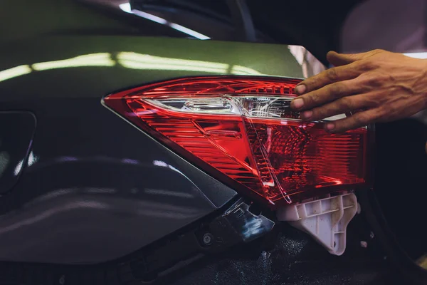 mechanic matching automobile headlight lamp to damaged car at repair service station.