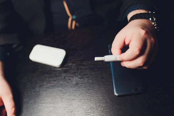 Technologie voor het verwarmen en niet verbranden van tabaksproducten. Man die e-sigaret in zijn hand houdt voor het roken. — Stockfoto