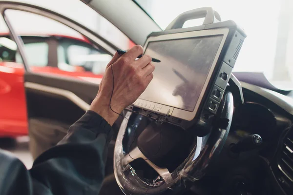 Mecánico del coche mantiene un vehículo con la ayuda de una computadora de diagnóstico tecnología moderna en el taller de reparación de automóviles . —  Fotos de Stock