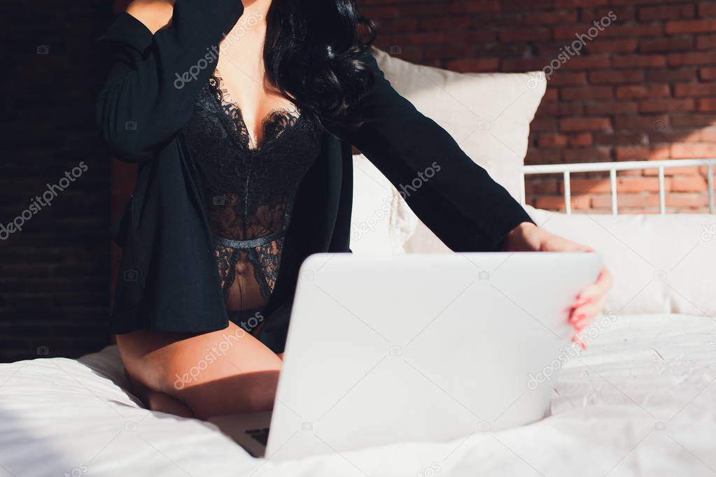 Beautiful, young girl posing in front of a web camera, working as a sexual model. The concept of online flirting, sex on the Internet.