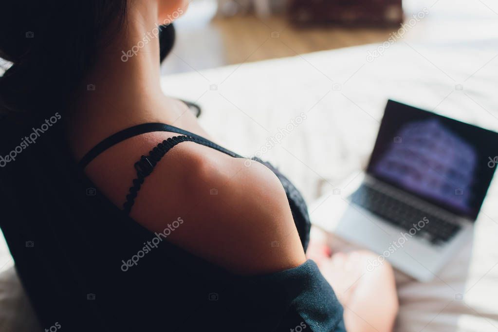 Beautiful, young girl posing in front of a web camera, working as a sexual model. The concept of online flirting, sex on the Internet.