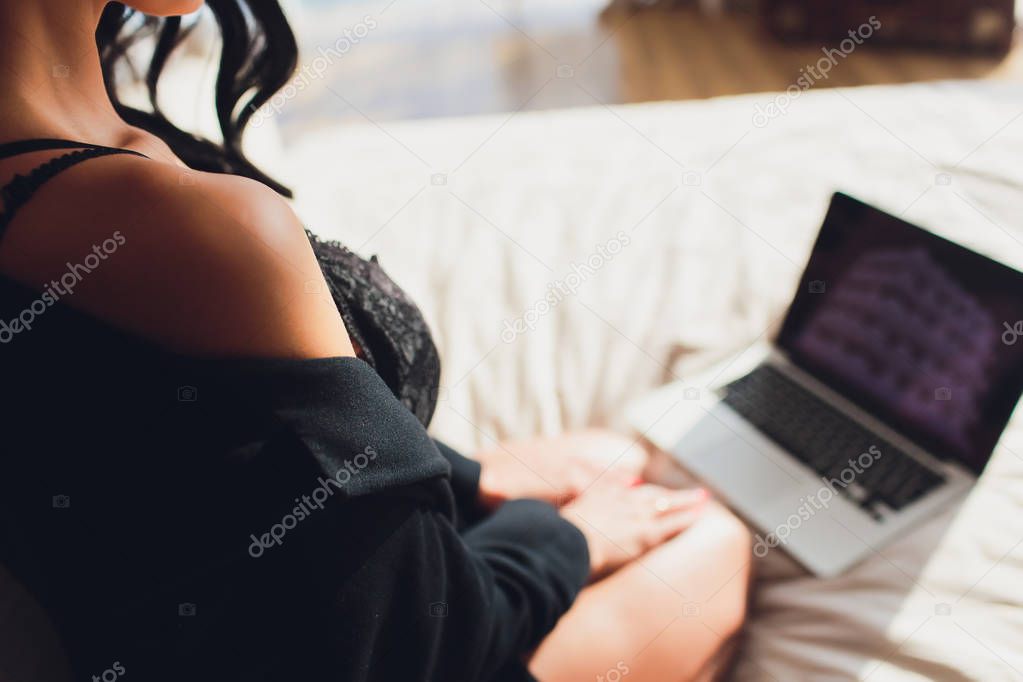 Beautiful, young girl posing in front of a web camera, working as a sexual model. The concept of online flirting, sex on the Internet.