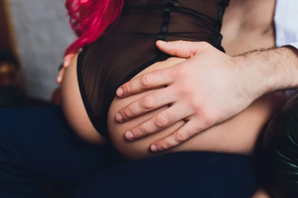 Man håller händerna på kvinnlig skinkor av ung kvinna med smal kropp och ben med nakna rygg i underkläder. — Stockfoto