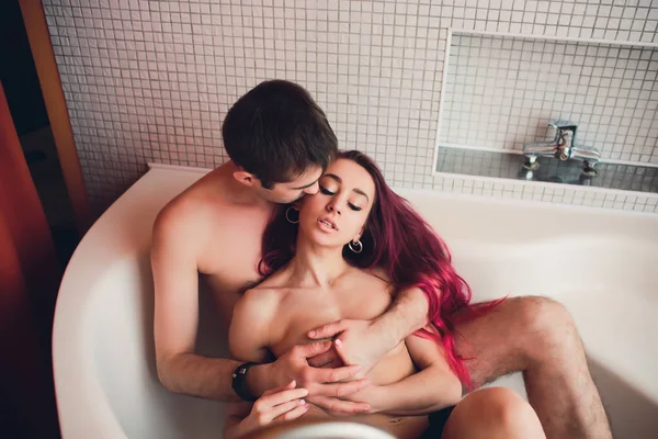 Man hugs woman from behind lying in the bath.