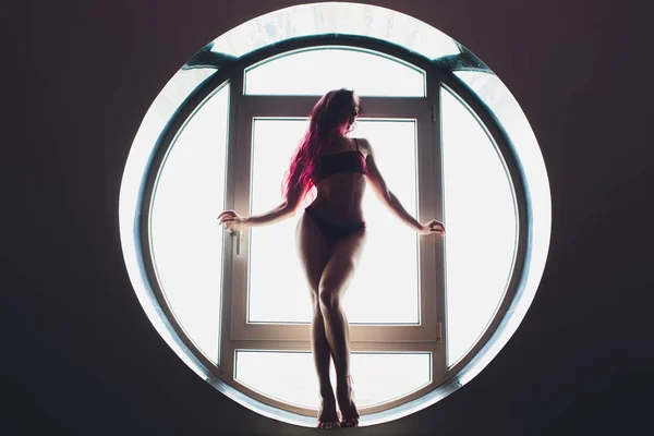 La silhouette sombre d'une belle femme sur le fond de la fenêtre ronde. yoga, acrobatie . — Photo