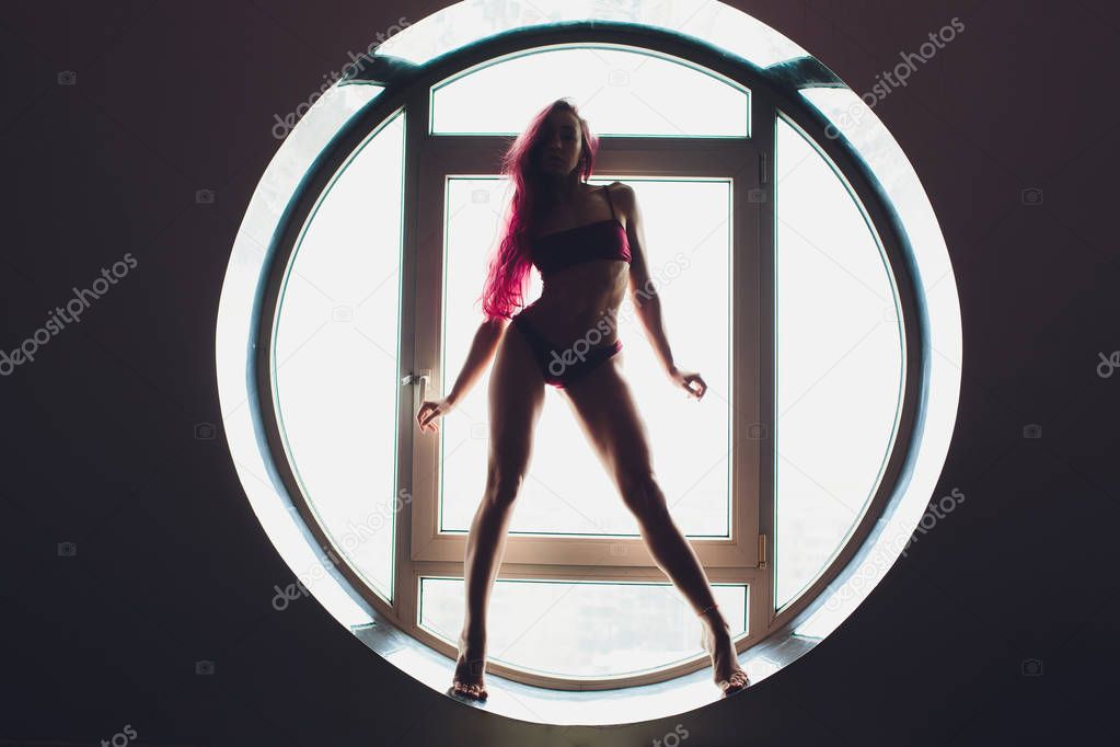 The dark silhouette of a beautiful woman on the background of the round window. yoga, acrobatics.