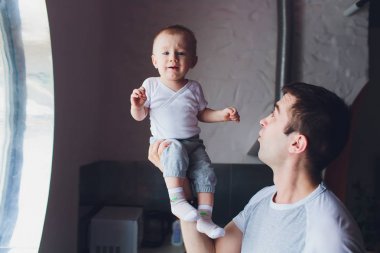 Genç, mutlu bir baba oğlunu başının üstünde tutuyor..
