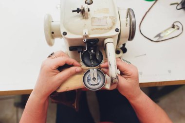 Ev yapımı dikiş makinesinin bakımını yapan kadın eller..