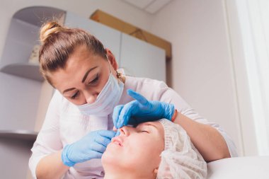 Doktor kozmetik uzmanı güzellik salonunda güzel bir kadının dudak büyütme prosedürünü yapıyor. Kozmetik cilt bakımı..