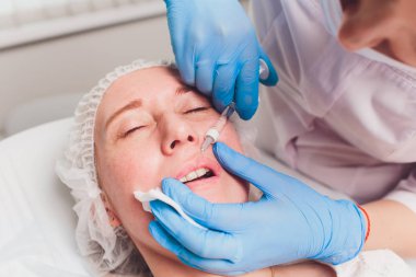 Doktor kozmetik uzmanı güzellik salonunda güzel bir kadının dudak büyütme prosedürünü yapıyor. Kozmetik cilt bakımı..