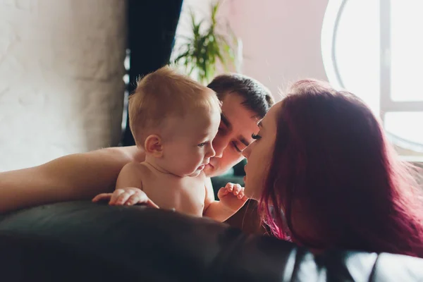 Padres felices con adorable niñita sentada en el sofá en casa, disfrutando de la paternidad, familia feliz joven, nuevo concepto de vida . —  Fotos de Stock