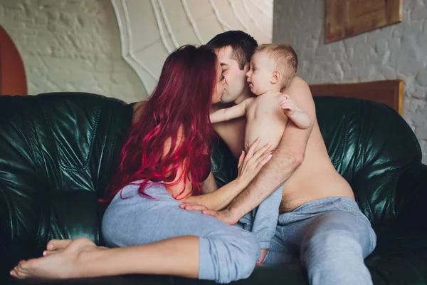 Happy parents with adorable little baby girl sitting on the couch at home, enjoying parenthood, young happy family, new life concept. — Stock Photo, Image