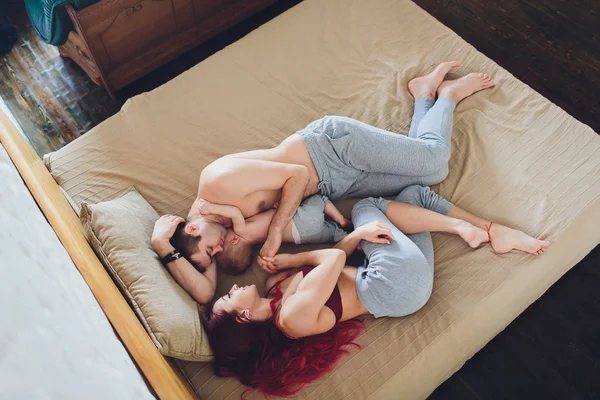 Pais jovens felizes com bebê na cama em casa . — Fotografia de Stock