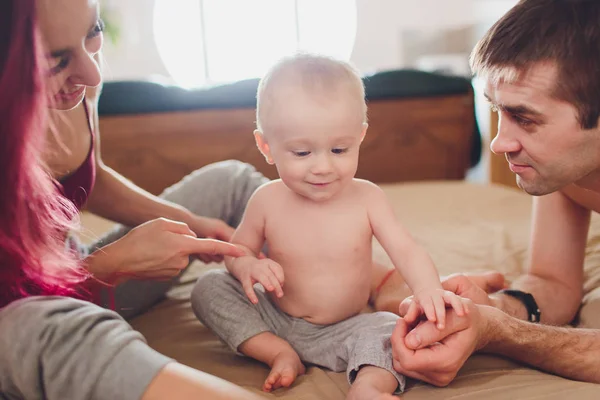 Padres felices con adorable niñita sentada en el sofá en casa, disfrutando de la paternidad, familia feliz joven, nuevo concepto de vida . — Foto de Stock