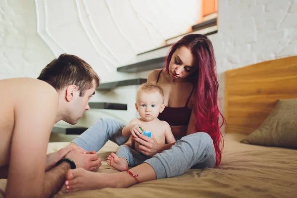 Padres jóvenes felices con el bebé en la cama en casa . —  Fotos de Stock