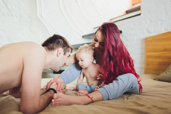 집에서 침대에서 아기와 함께 행복한 젊은 부모. — 스톡 사진