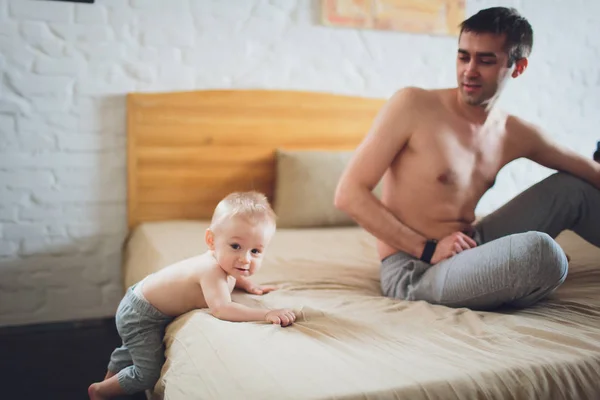 집에서 침대에 아기와 함께 젊은 아버지. — 스톡 사진