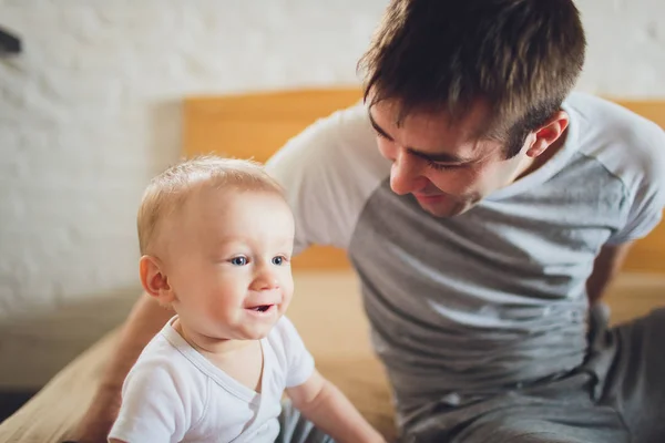 집에서 침대에 아기와 함께 젊은 아버지. — 스톡 사진