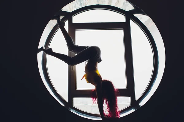 La silhouette sombre d'une belle femme sur le fond de la fenêtre ronde. yoga, acrobatie . — Photo