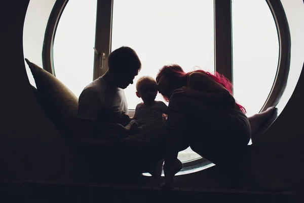 어머니, 아버지와 아이 아들의 행복한 가족이 큰 창문 근처 바닥에서 집에서 놀고 껴안고 있습니다.. — 스톡 사진