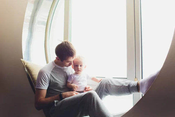 Smiling Father Standing By Window With Baby Son At Home. — Stock Photo, Image