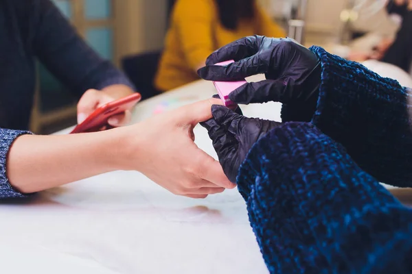 Händerna i handskar bryr sig om mans hand naglar. Manikyr skönhetssalong. — Stockfoto