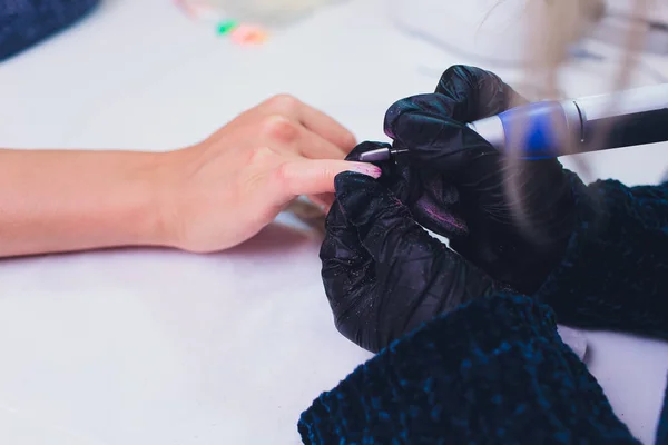 Hände in Handschuhen kümmern sich um die Nägel der Hände. Schönheitssalon für Maniküre. — Stockfoto