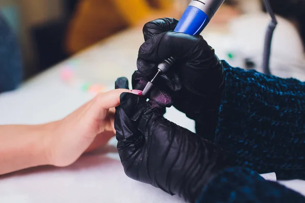 Hände in Handschuhen kümmern sich um die Nägel der Hände. Schönheitssalon für Maniküre. — Stockfoto