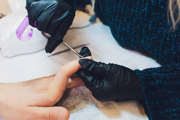 Hände in Handschuhen kümmern sich um die Nägel der Hände. Schönheitssalon für Maniküre. — Stockfoto