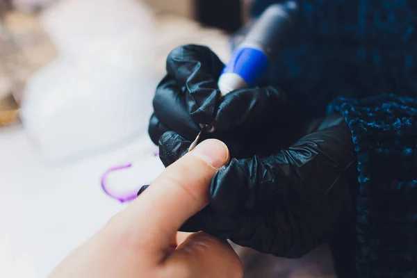 Hände in Handschuhen kümmern sich um die Nägel der Hände. Schönheitssalon für Maniküre. — Stockfoto