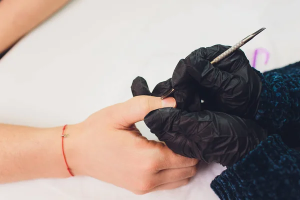 Hands in gloves cares about mans hand nails. Manicure beauty salon. — Stock Photo, Image