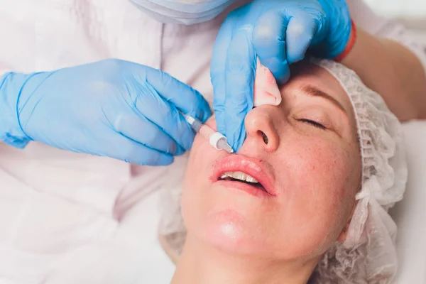 De arts cosmetoloog maakt Lip augmentatie procedure van een mooie vrouw in een schoonheidssalon.. — Stockfoto