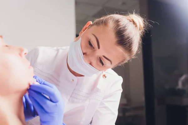 Il medico cosmetologo fa la procedura di iniezioni facciali per stringere e levigare le rughe sulla pelle del viso di una bella, giovane donna in un salone di bellezza. Cosmetologia cura della pelle . — Foto Stock