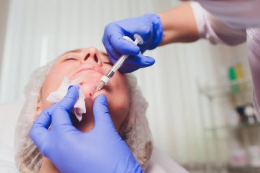 Doktor Kozmetolog, bir güzellik salonunda güzel, Genç bir kadının yüz derisi üzerinde kırışıklıkları sıkma ve yumuşatma için yüz enjeksiyonları prosedürü yapar. Kozmetoloji Cilt Bakımı.