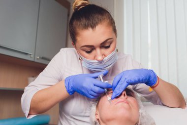 Doktor Kozmetolog, bir güzellik salonunda güzel, Genç bir kadının yüz derisi üzerinde kırışıklıkları sıkma ve yumuşatma için yüz enjeksiyonları prosedürü yapar. Kozmetoloji Cilt Bakımı.