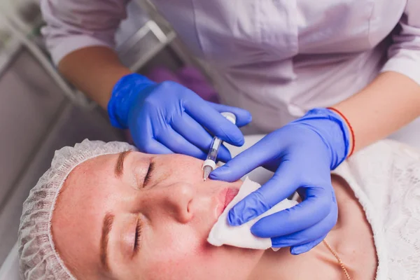 Dokter kosmetolog membuat prosedur injeksi wajah untuk mengencangkan dan merapikan keriput di kulit wajah seorang wanita muda yang cantik di salon kecantikan. Kosmetologi perawatan kulit . — Stok Foto