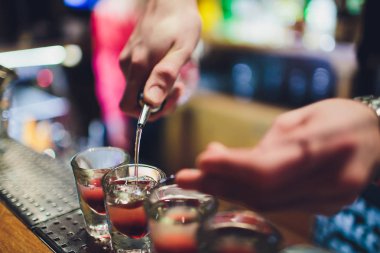 Barmen adam profesyonel bir yazıcı ile pub bar sıcak alkol çekim yapma. Barmen, bir bardak daha hafif ışıklar. Gece kulübünde rahatlayın. Sıcak ateş içer. Parti sağlar.
