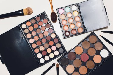 Makyaj fırçaları ve makyaj göz farları beyaz bir arka plan üzerinde.