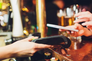 NFC teknolojisiyle ödeme yapan kadın cep telefonunda, restoranda, kafede, barda.